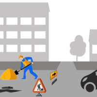 Un ouvrier travaille sur une route, entouré d'une voiture et d'équipements de construction.