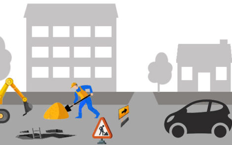 Un ouvrier travaille sur une route, entouré d'une voiture et d'équipements de construction.