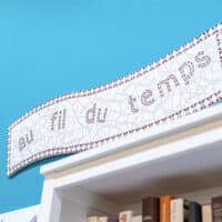 Lettres Au fil du temps accroché au mur au-dessus d'une étagère de livres.