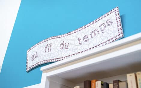 Lettres Au fil du temps accroché au mur au-dessus d'une étagère de livres.