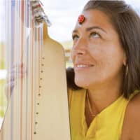 Une femme souriante, joue de la harpe.