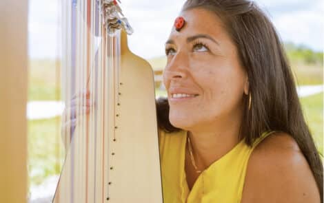 Une femme souriante, joue de la harpe.