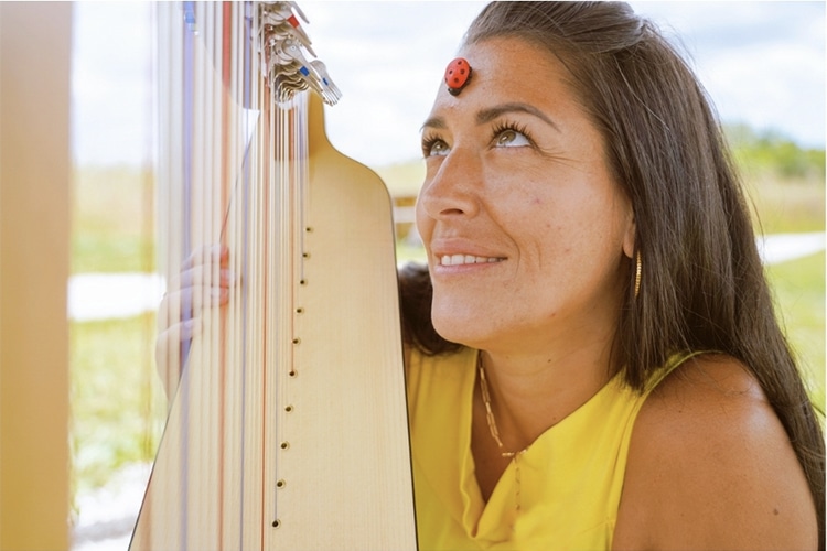 Une femme souriante, joue de la harpe.