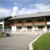 Groupe d'enfants assis devant un centre d'hébergement de loisirs.