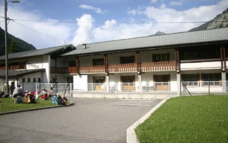 Groupe d'enfants assis devant un centre d'hébergement de loisirs.