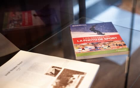 Livres dédiés au sport posés sur une vitrine d'exposition.