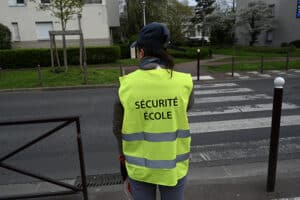 Un agent de point école, de dos avec son gilet de sécurité fluo.