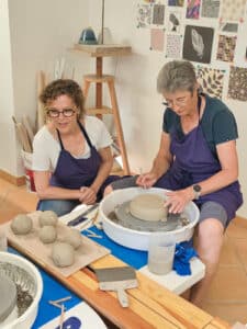 Une élève du cours de poterie en apprentissage sous les conseils de l'enseignante.