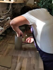 L'enseignante du cours de poterie conçoit un objet de ses mains.