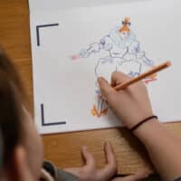 Un enfant dessine sur un papier.