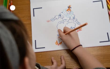 Un enfant dessine sur un papier.