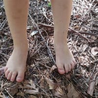Une personne debout sur le sol de la forêt, pieds nus,