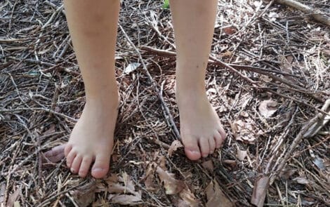 Une personne debout sur le sol de la forêt, pieds nus,