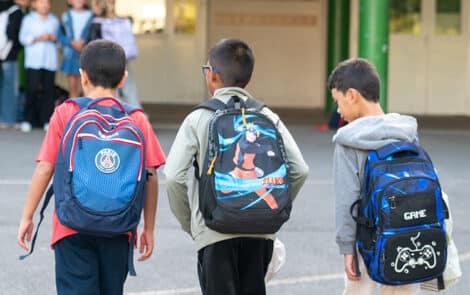 3 jeunes enfants, cartable au dos, se rendent à l'école.